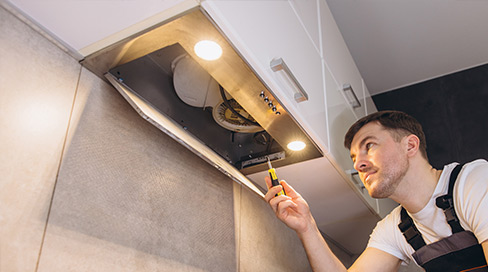 Technician testing airflow and motor performance of a new range hood